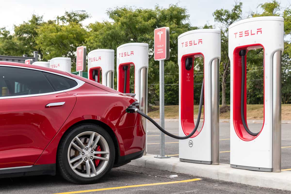 Rear of red Tesla Model S while charging at Tesla Supercharger Station.