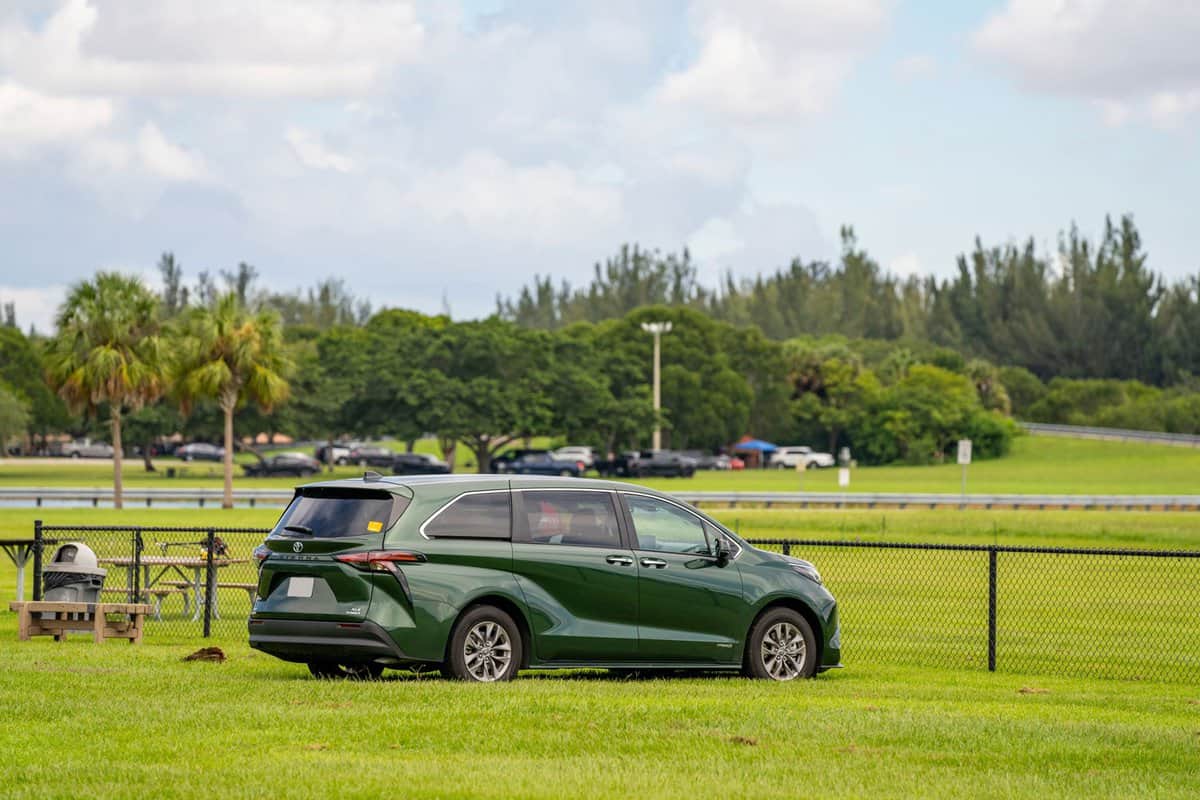Rear quarter view of a 2021 Toyota Sienna All Wheel Drive hybrid minivan parked on green grass