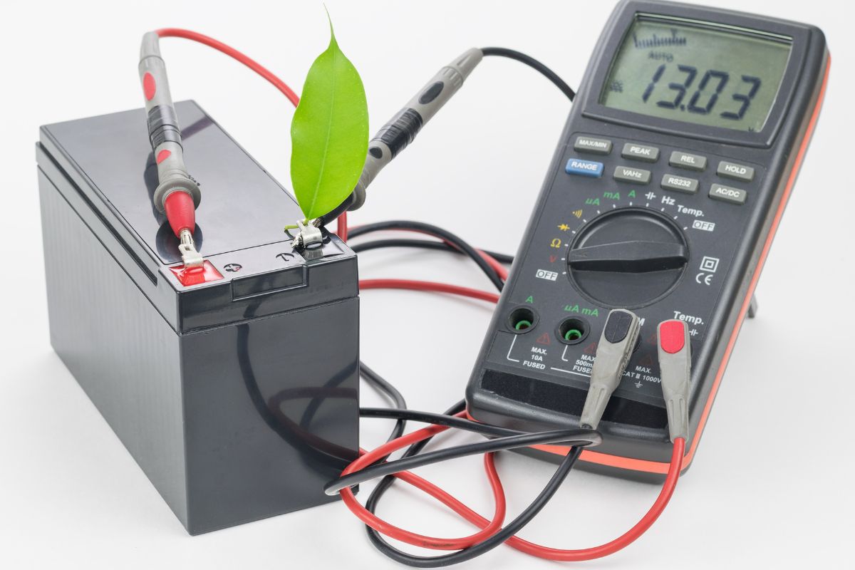 Rechargeable battery with connected measuring instrument and green leaf. The concept of clean energy.