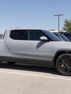 Can Rivian Drivers Use Tesla Chargers?, Rivian R1T Pickup Truck display at a dealership. Rivian offers the R1T in Explore, Adventure and Launch models.