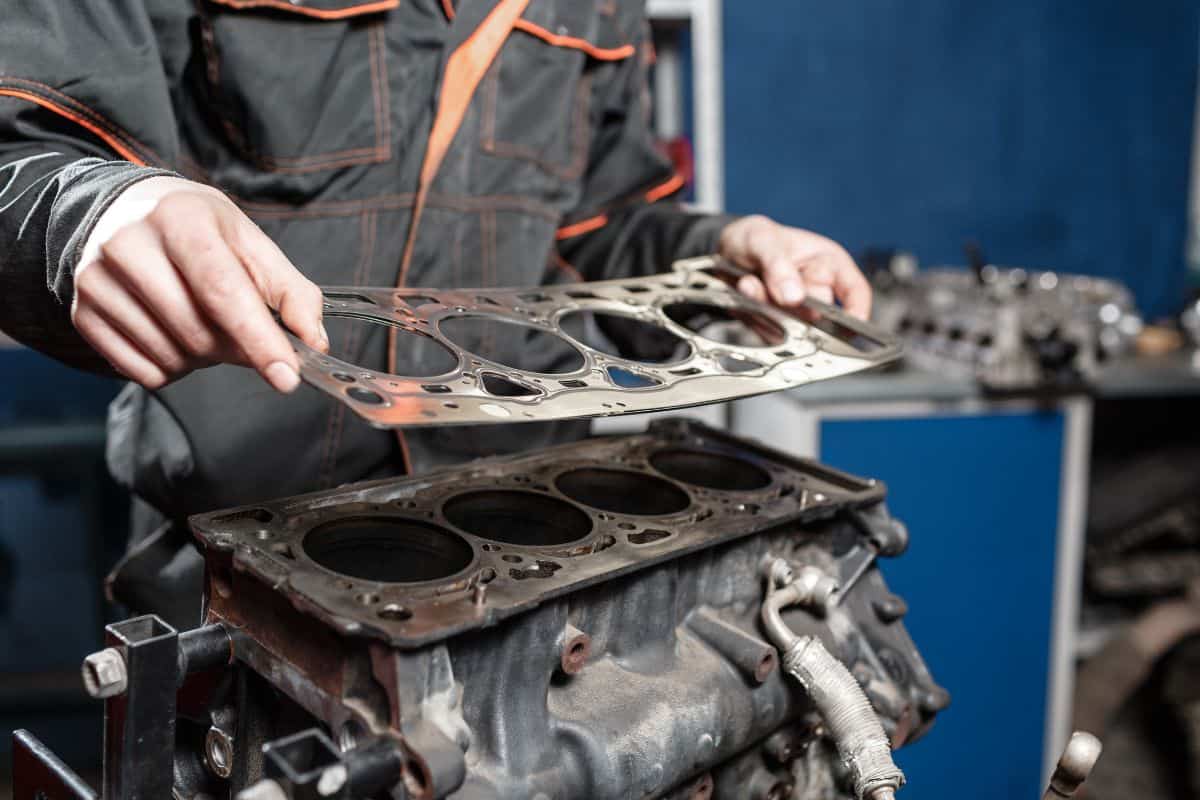 Sealing gasket in hand. The mechanic disassemble block engine vehicle. Engine on a repair stand with piston and connecting rod of automotive technology. 