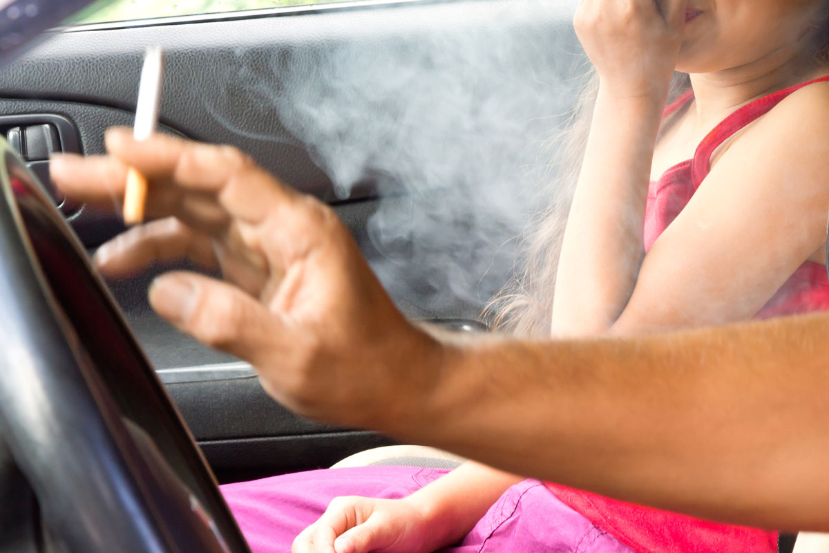 Father smoking cigarette and the child choking of smoke in a car