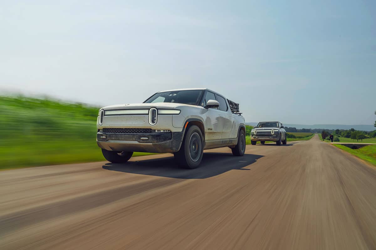 White Rivian cruising down the road after camping