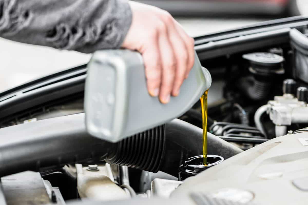 Woman putting oil into the engine of her car having opened the bonnet