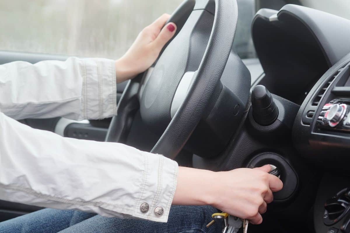 Women driver hand inserting car key and starting engine