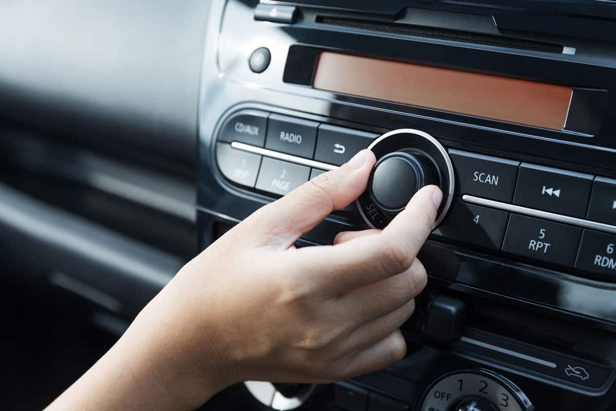 Women turning button on car radio for listening to music