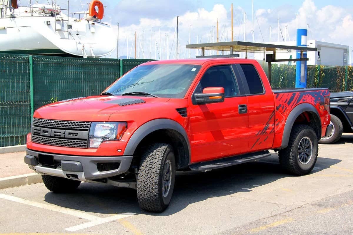 glossy red Ford f150 parked on the road side
