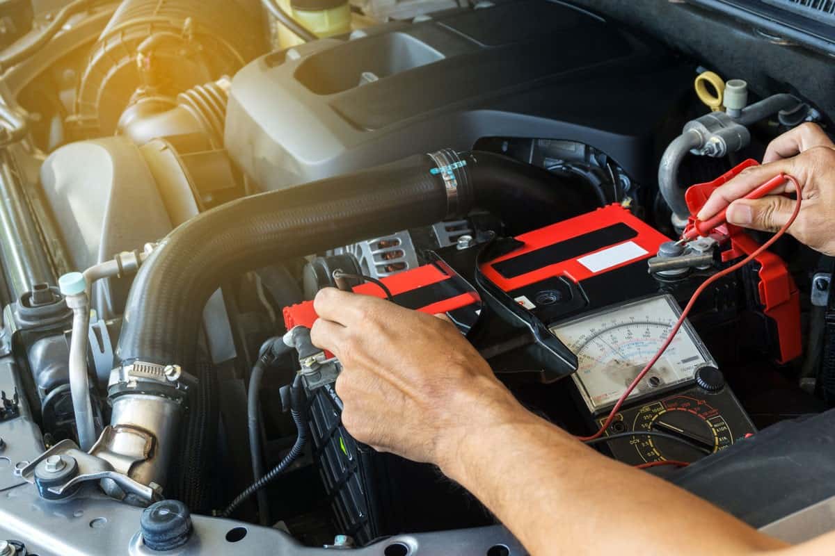 mechanic car service using multimeter check low battery