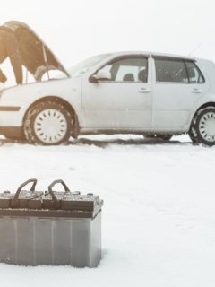 Man repairs a car in winter on snow in the background is a discharged battery, Will A Block Heater Help A Dead Battery?