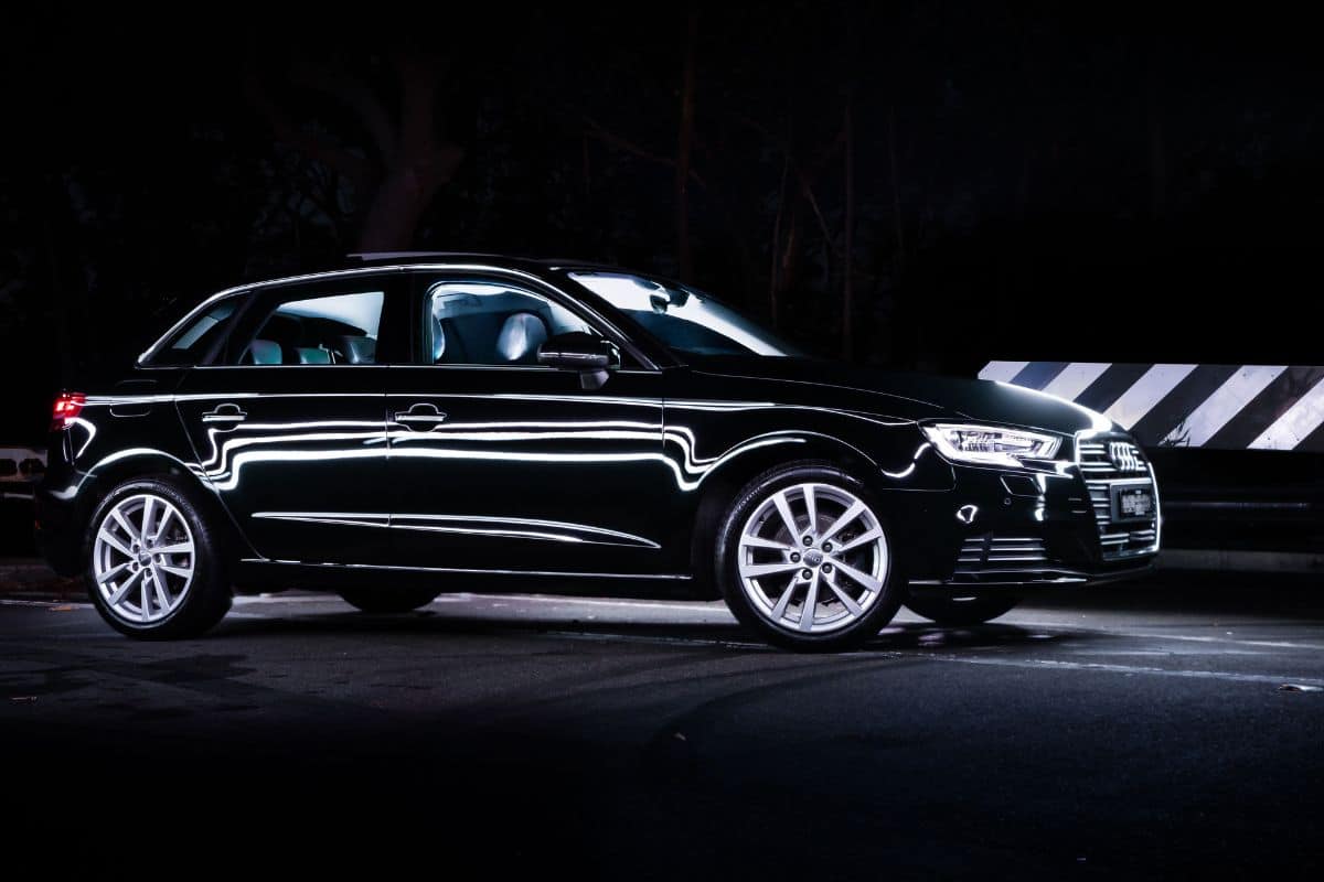 A shiny black Audi A3 car on a road at night