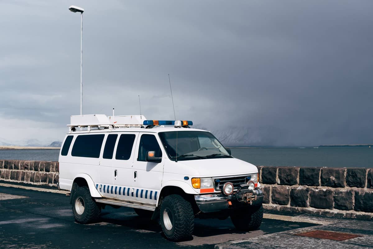 A white Ford Econoline van on huge wheels, with sirens and flashing lights, parked on the waterfront in Reykjavik, Iceland.