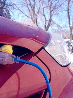 Block heater cable plugged into a vehicle parked in a snowy winter driveway, How Many Amps Does A Block Heater Draw?