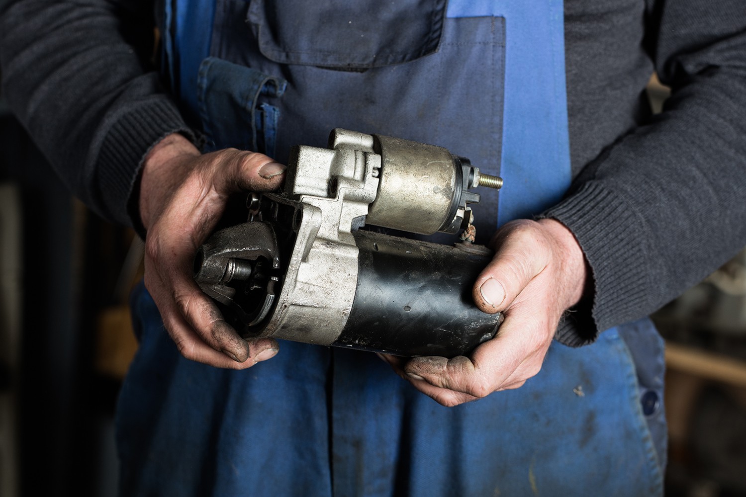 Car mechanic hand holding old car starter gear