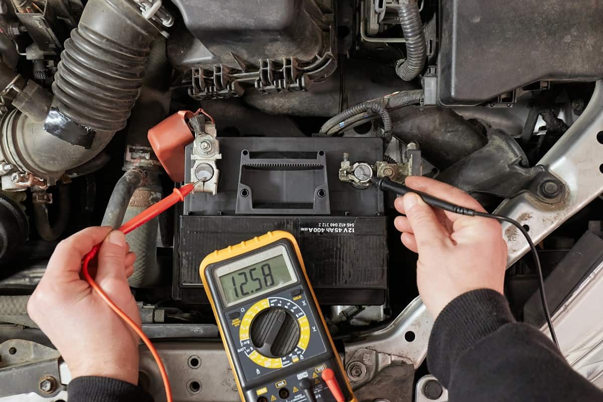 Car starter battery voltage measured with multimeter in a repair garage