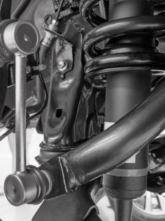 Close up Link stabilizer front mounted under the suspension of the car black and white, How Long Does It Take To Replace Sway Bar Links