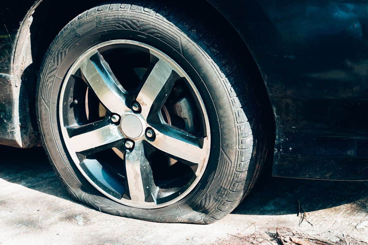 Close up of a car flat tire, air tire pressure lose on the road.