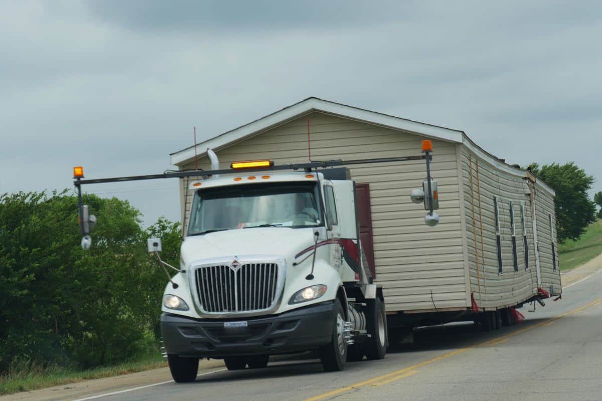 Close up side view of a a trailer truck transporting a mobile home on the road
