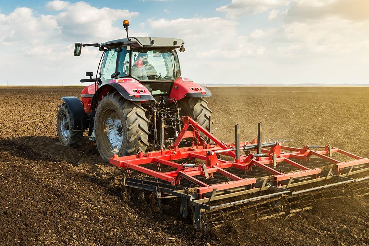 Farmer in tractor preparing land with seedbed cultivator as part of pre seeding activities in early spring season