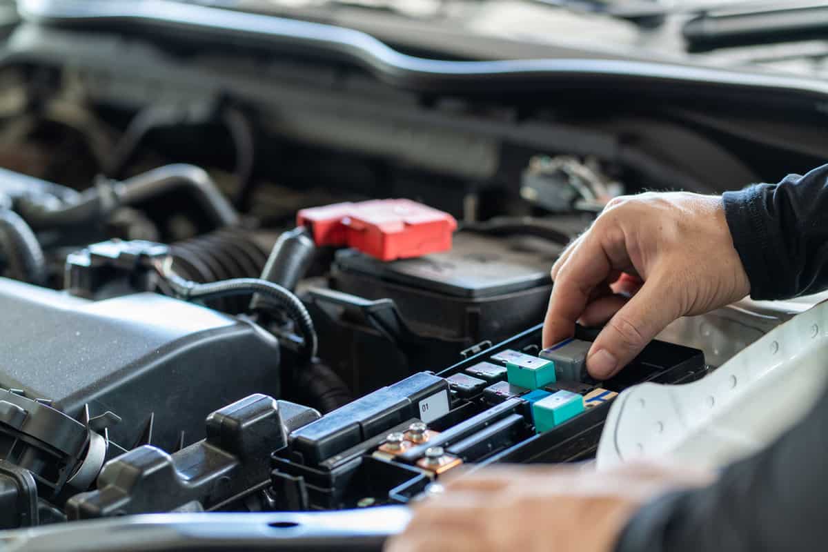 Mechanic man holding standard relay switch of the car for checked, repair and maintenance 