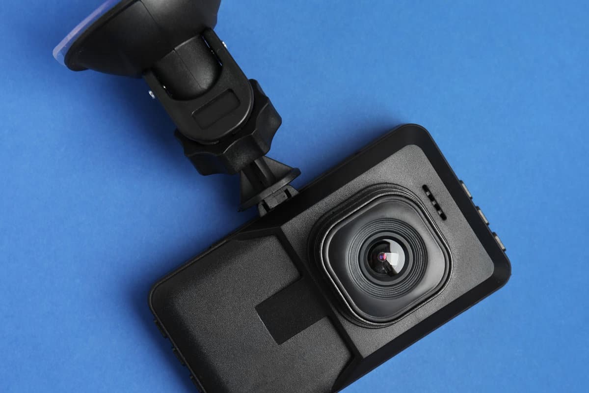Modern car dashboard camera with suction mount on blue background, top view 