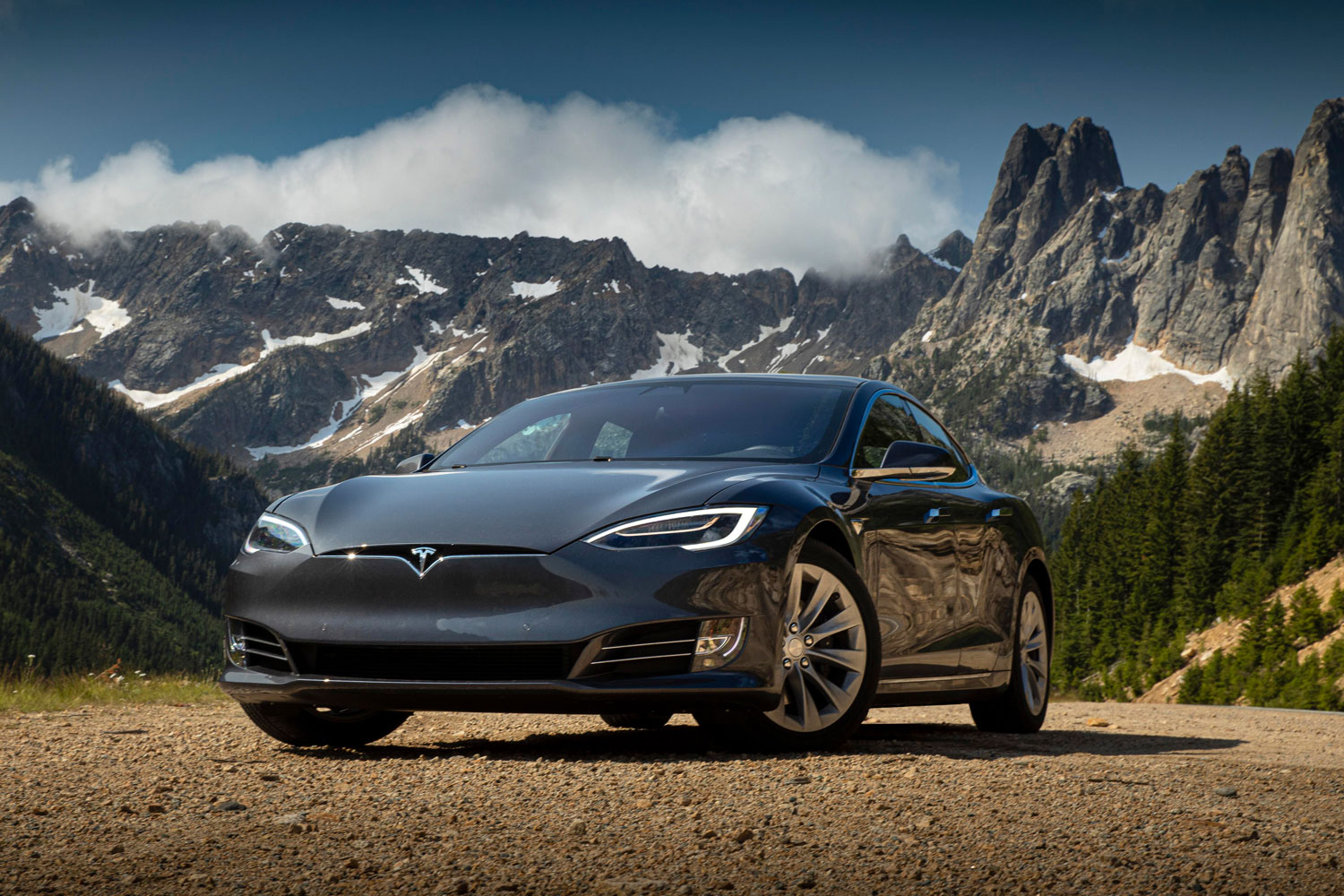 Photograph of a Tesla model 3 in front of a mountain in the wilderness of Canada.