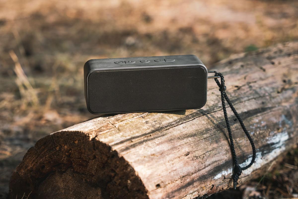 Portable wireless speaker for listening to music on a log in the forest