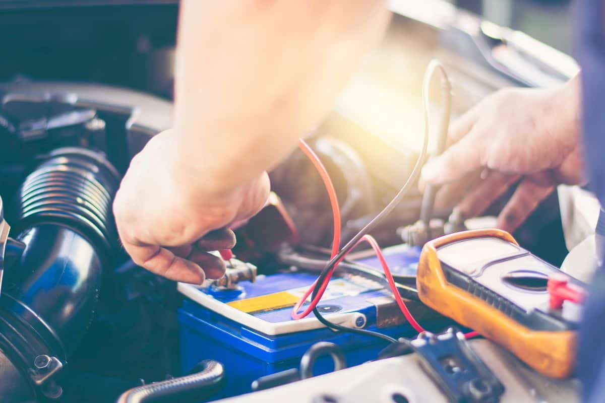 An auto mechanic uses a multimeter voltmeter to check the voltage level in a car battery