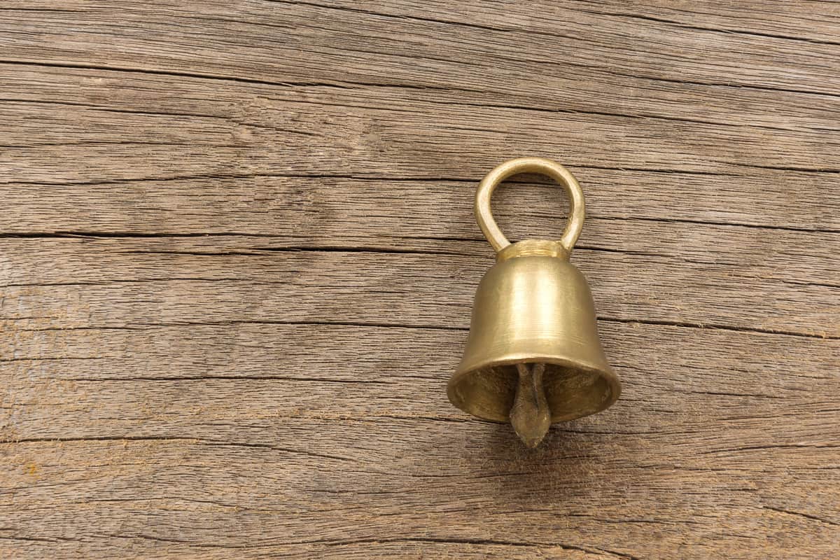 Small gold bells are handmade from cast brass work and polishing, glitter. Placed on the wooden floor.
