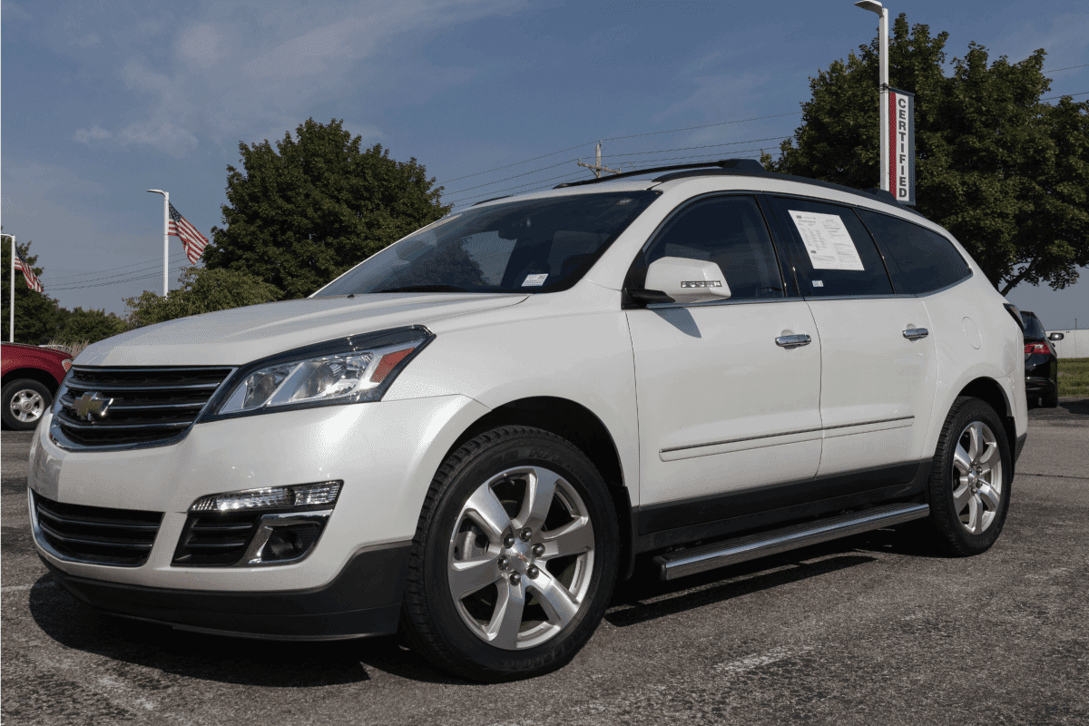 Used white Chevrolet Traverse on display at a car dealership under the sun 