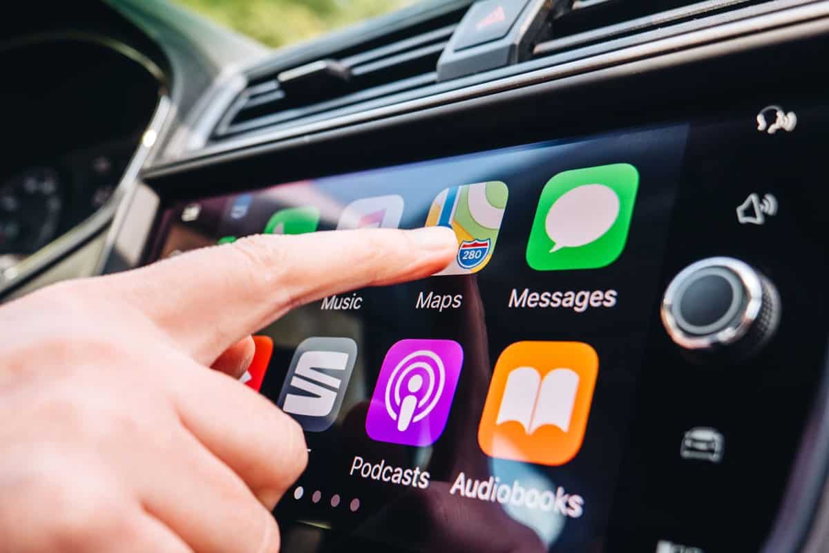 Woman pressing Apple Maps button on the Apple CarPlay main screen in modern car