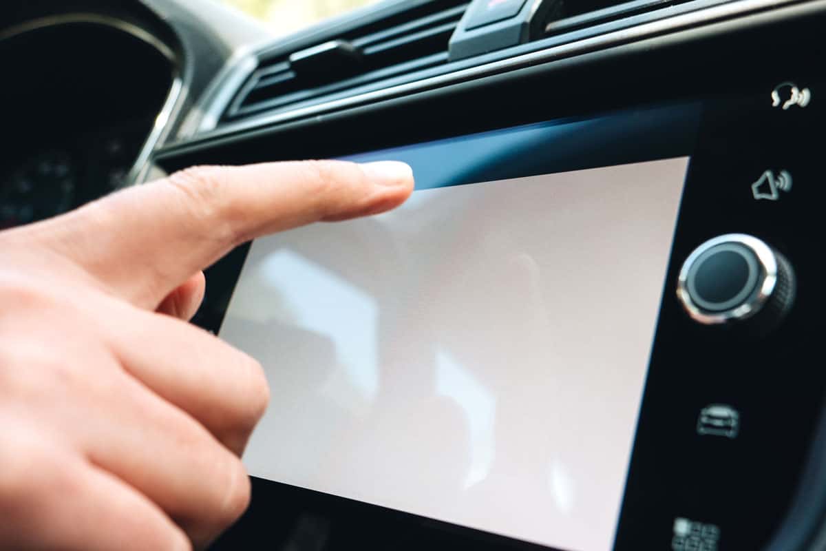 Woman pressing button on the white empty main screen in modern car dashboard
