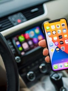 male driver holding new iPhone 12 Pro smartphone with infotainment car computer, My BMW Carplay Is Not Working - Why? What To Do?