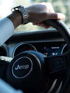 man holding jeep car vehicle steering wheel on a sunny summer day, My Jeep ABS And Traction Control Light Is On - Why? What To Do?