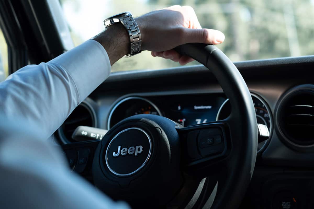 man holding jeep car vehicle steering wheel on a sunny summer day