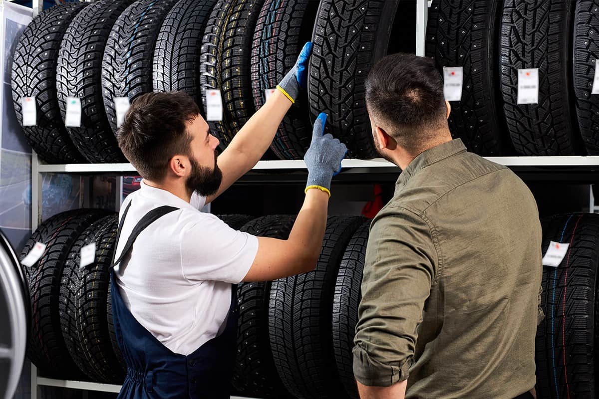 Male salesman showing wheel tires to caucasian man customer
