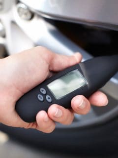 Man checking the tire pressure using a high tech sensor, Are Tire Pressure Sensors Universal?