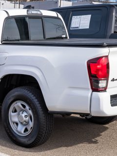 A used, white Toyota Tacoma pickup truck for sale at a dealership on a sunny winter day, How To Lock A Tacoma Tailgate