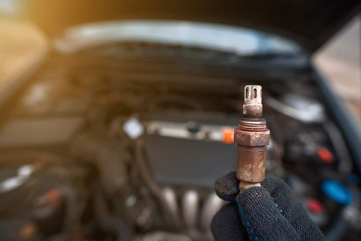 Man hold in hand faulty old oxygen sensor of exhaust system
