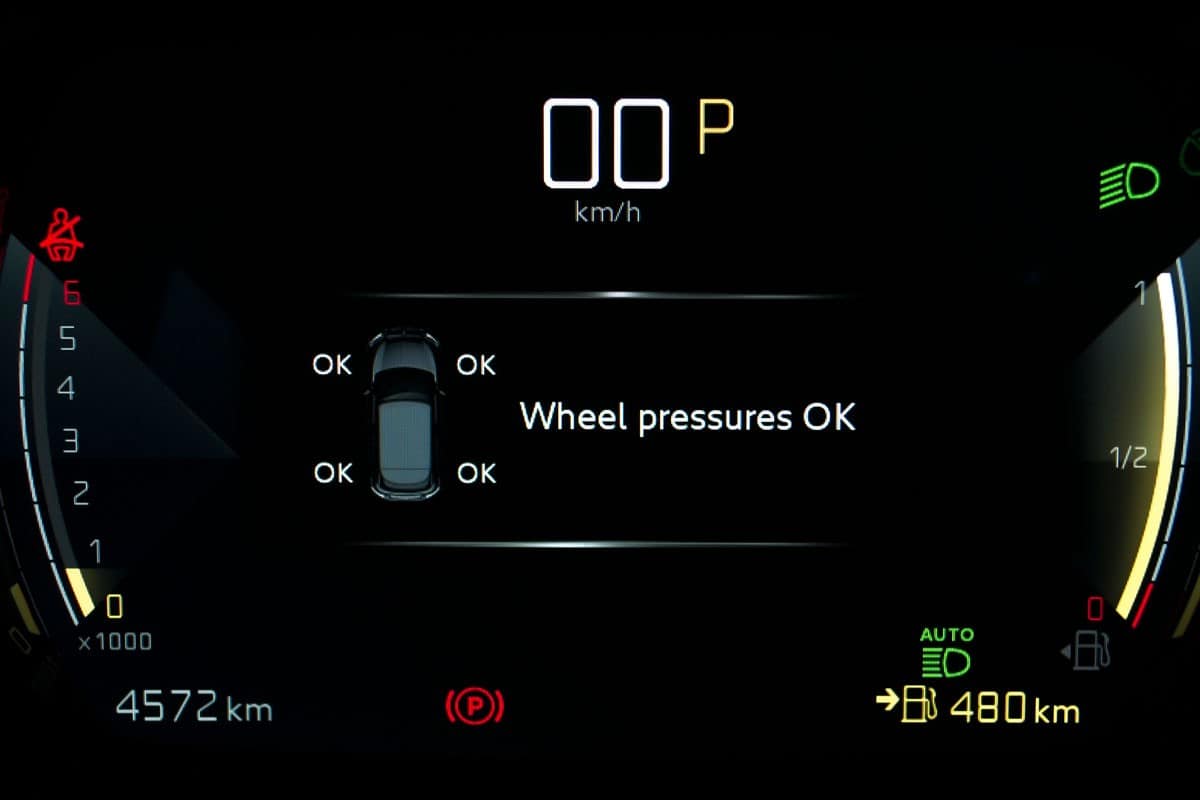 TPMS (Tyre Pressure Monitoring System) monitoring display on car dashboard panel. Checking tires pressures. Car instrument panel with speedometer, tachometer, odometer, fuel gauge, seatbelt reminder. 