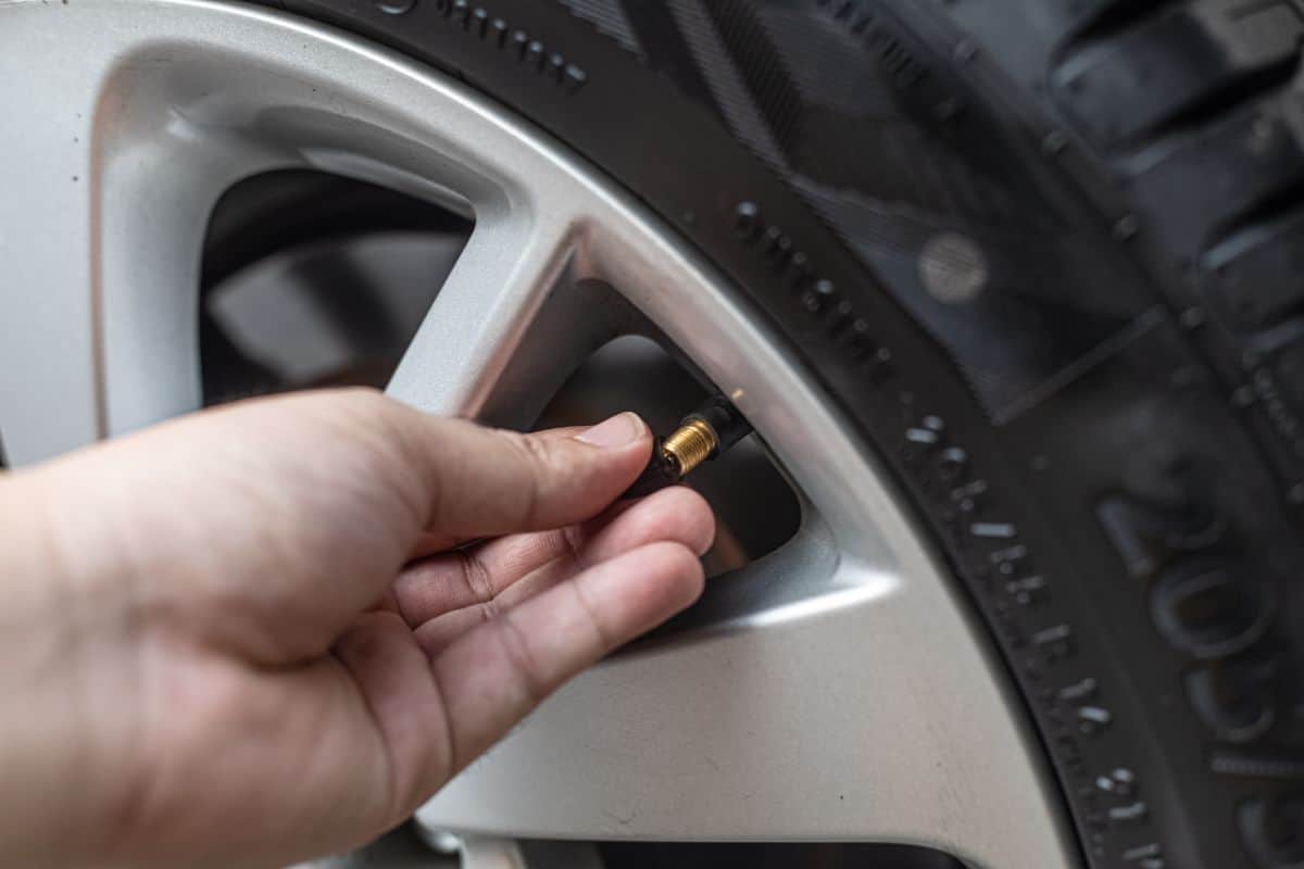 The hands of the man who is checking the tire pressure.