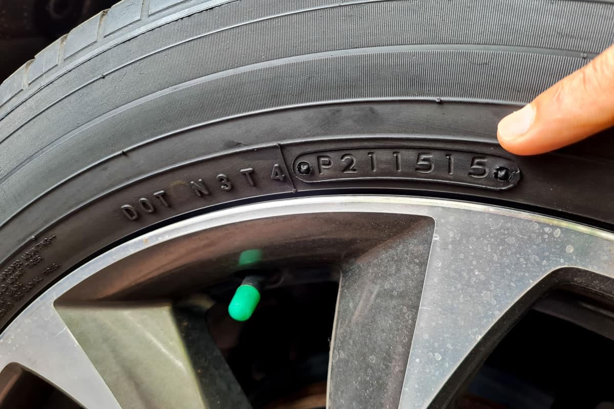 car tire production code. the finger shows the writing on the tire which informs the production date data and tire expiration date code 