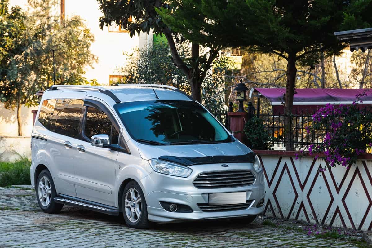silver Ford Transit Connect is parked on the street in city against the backdrop of a city