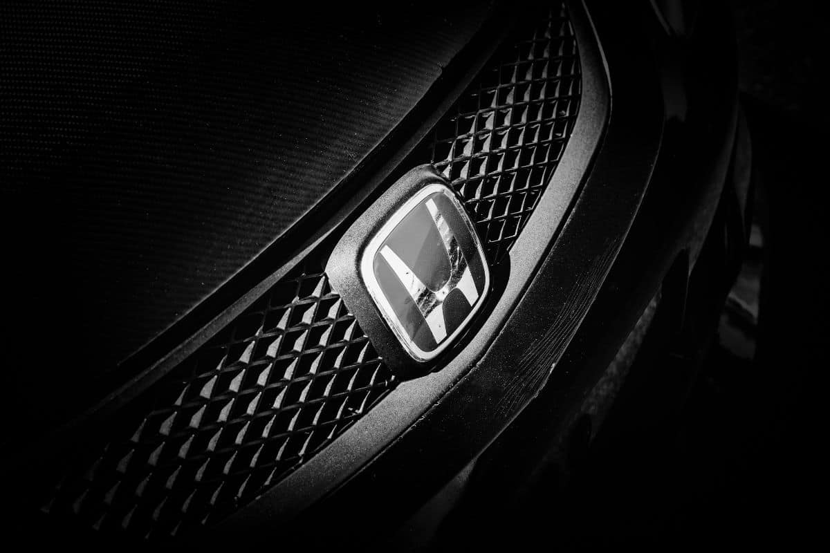 A closeup of a Honda badge on the front grille of a Honda Civic.