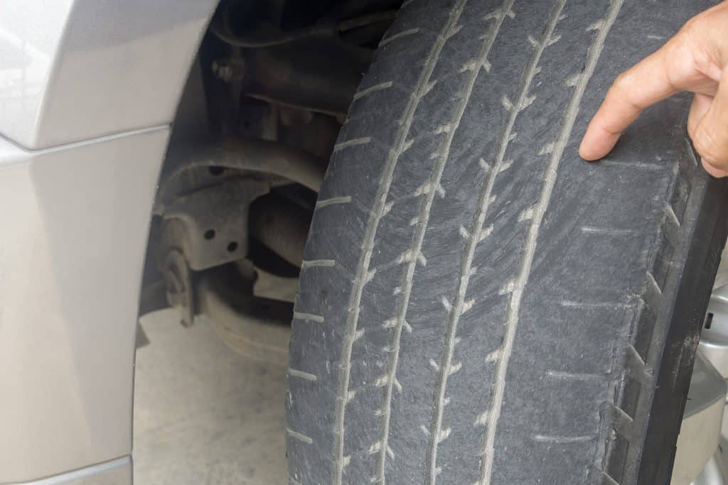 Man finger pointing to damage on tire tread