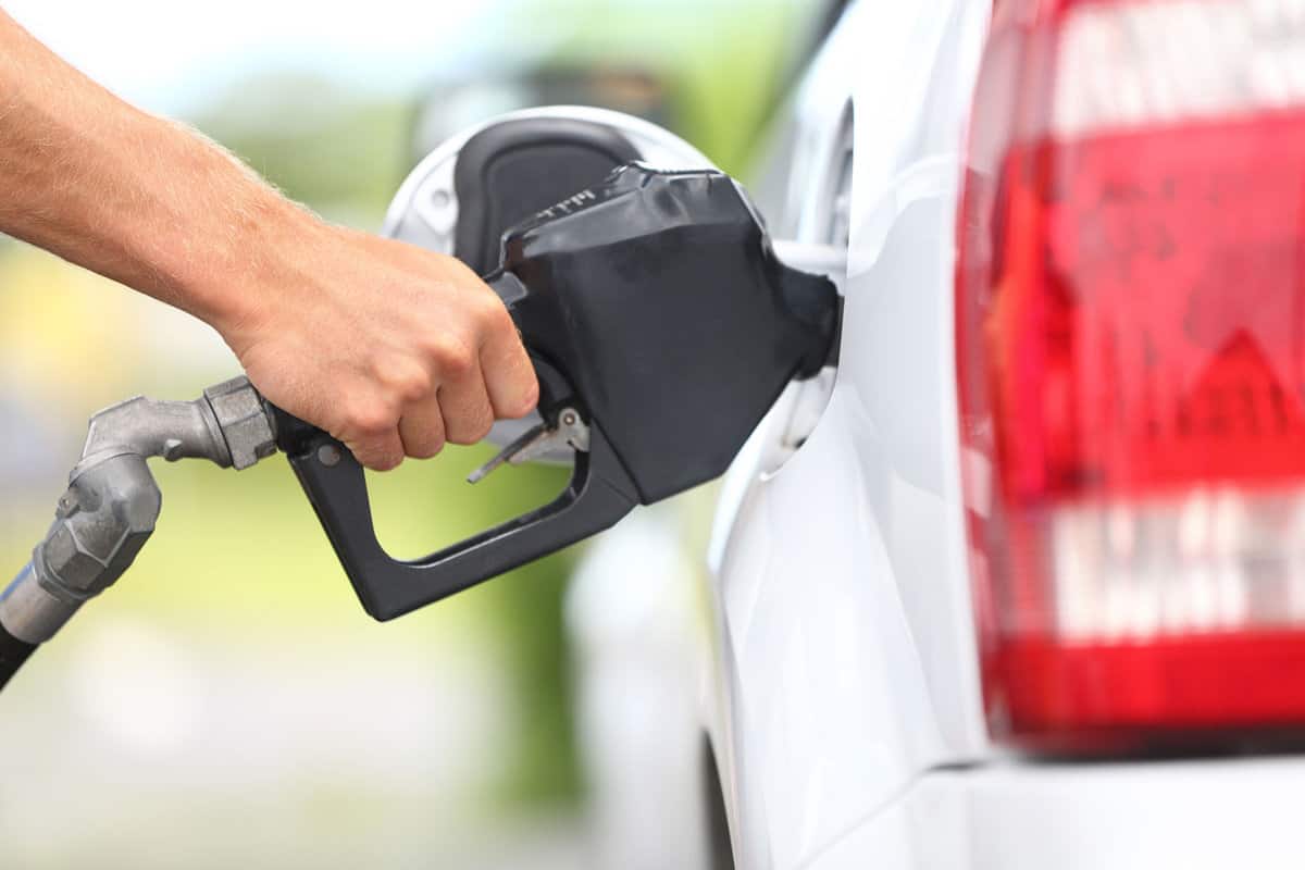 Pumping gas at gas pump. Closeup of man pumping gasoline fuel in car at gas station.
