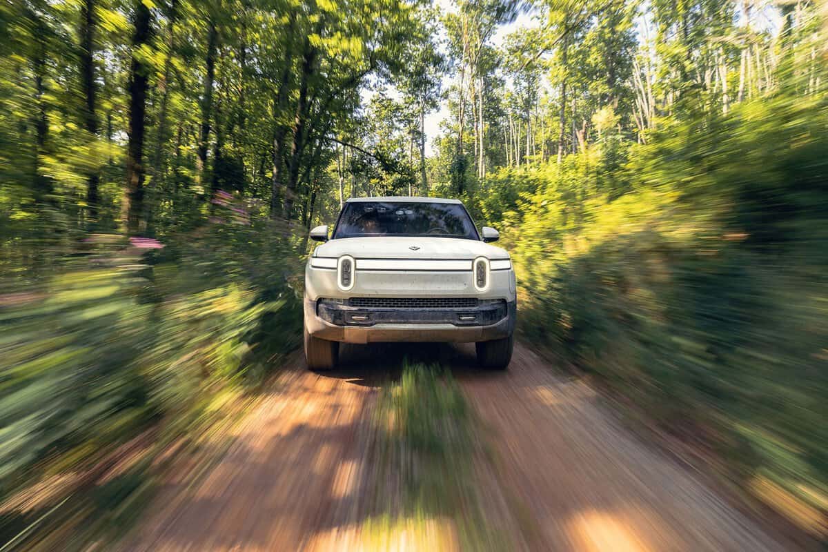 The electric pickup truck, Rivian R1T, is in motion, demonstrating its power and performance.
