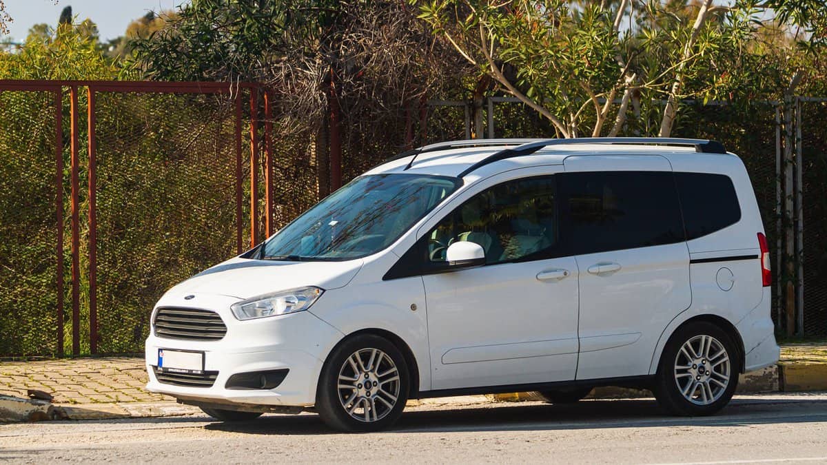 A white Ford Transit Connect on the side of the road