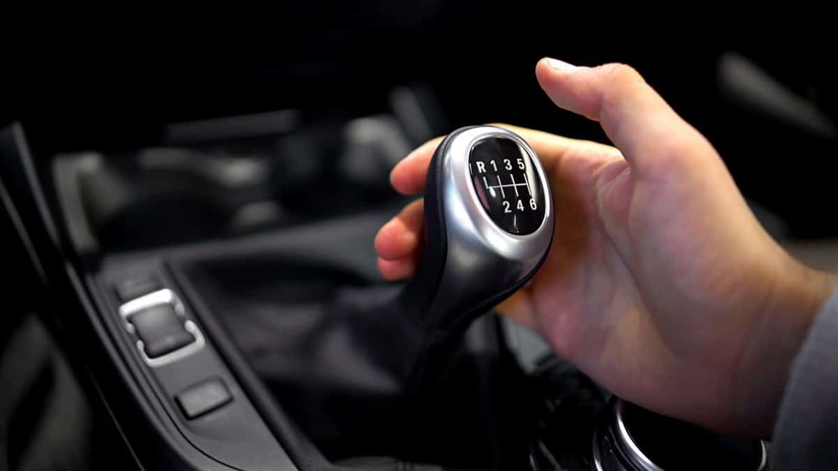 Male hand holding manual gearbox in car, test drive of new automobile, closeup