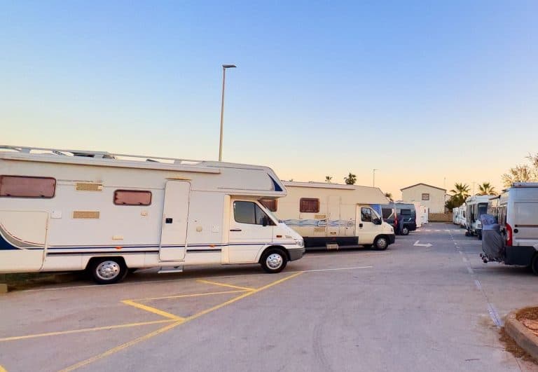 A line of RVs parked in a parking lot
