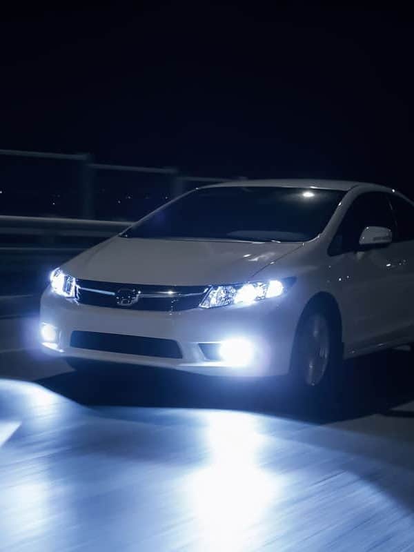 Car with xenon headlights fast drive on road at night